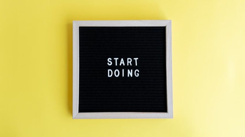 Black message board with 'Start Doing' on a bright yellow background for inspiration.